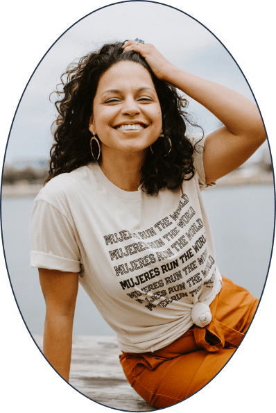 A woman is smiling and wearing a t-shirt that says Mujeres run the world.
