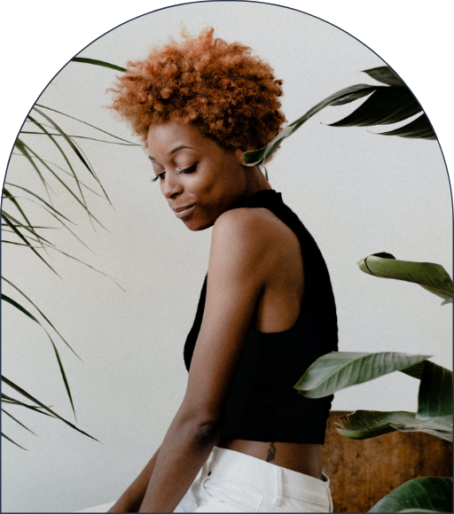Woman looking down with plants around her.