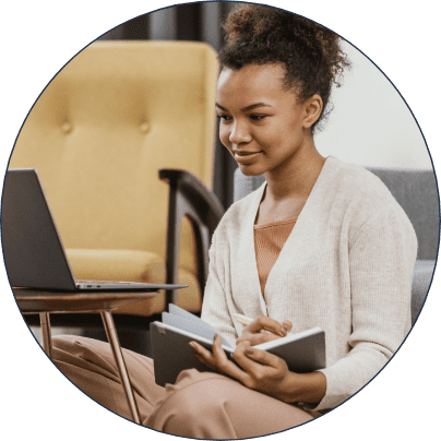 Woman taking notes while looking at her laptop