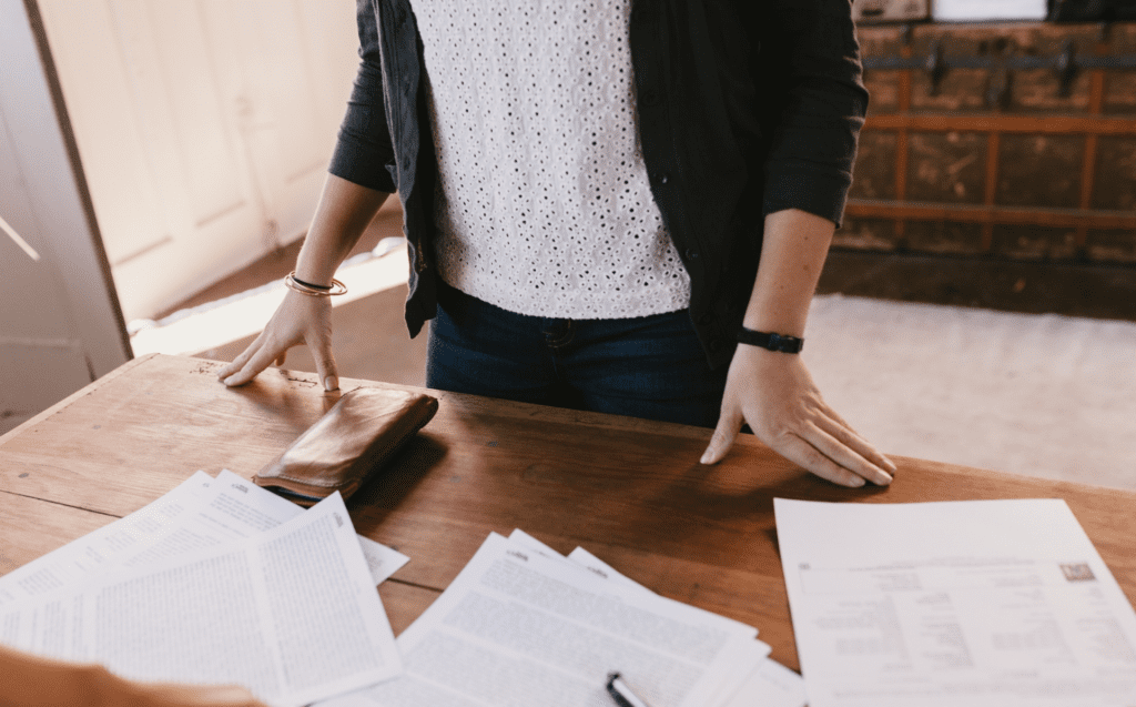 Woman leaning over desk with paperwork laid on the table