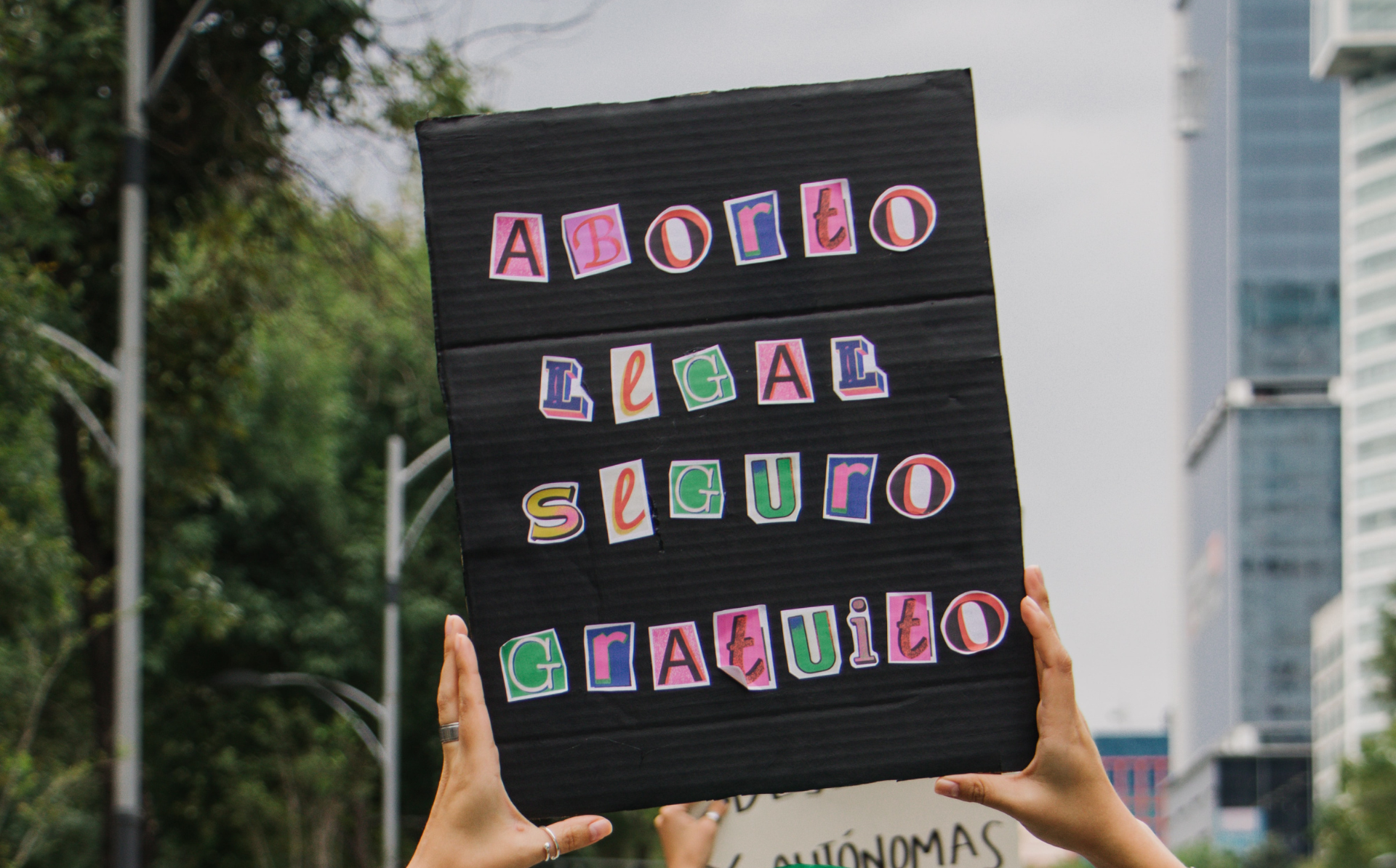 Woman holding sign in Spansih at reproductive rights protest which says, "Aborto legal, segura, gratuito," translating in English to "Safe, free, and legal abortion." Rallies in Latin America have been influenced by the historic 1979 Roe v. Wade ruling.
