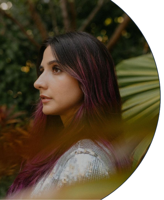 Profile photo of disability activist and model Paula Carozzo facing left with a background of trees and palm trees