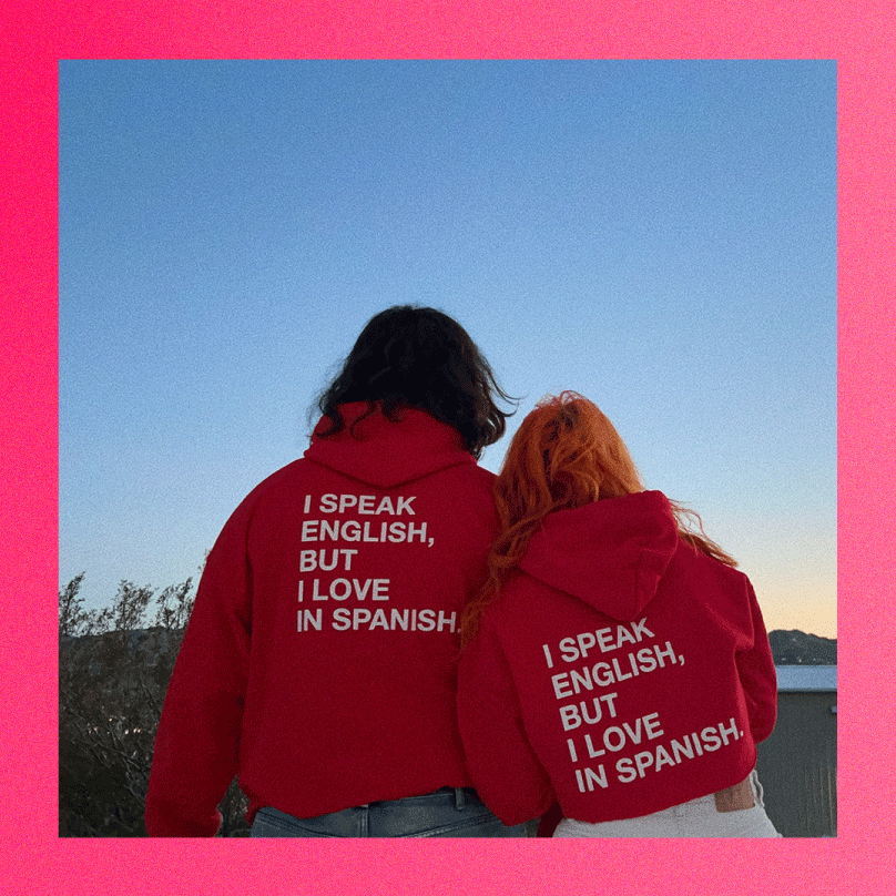 A man and a woman standing next to eachother but pictured from the back wearing an 'I Speak English But I Love In Spanish" hoodiel shown as a Galentine's Day or Valentine's Day gift