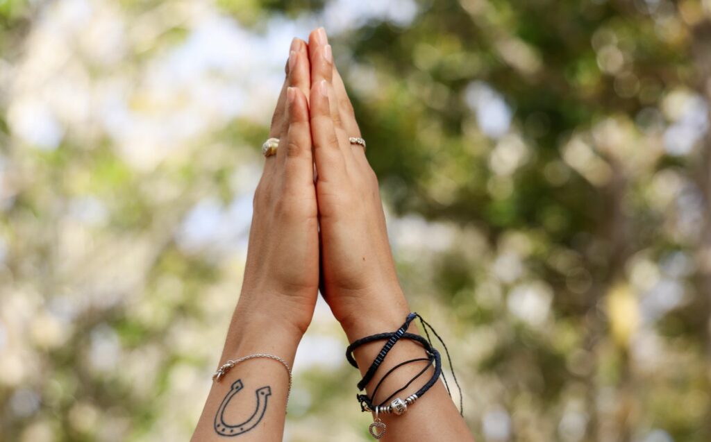 Two hands come together in prayer to honor the importance of Latinas caring for their mental health: