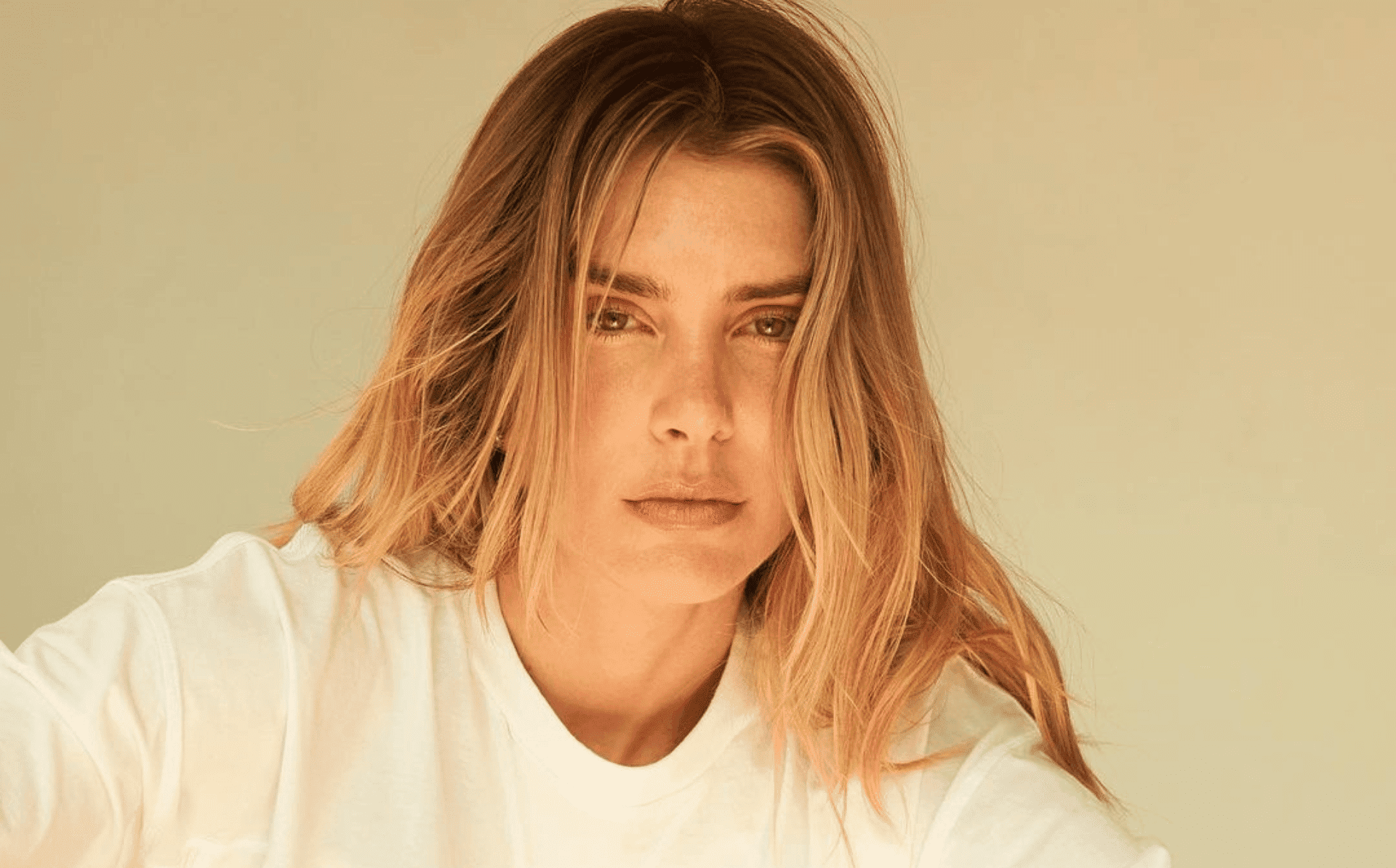 Supermodel and CEO of wellness brand KAPOWDER, Valentina Ferrer looks at the camera, wearing a white tee and her blonde hair down over her shoulders.