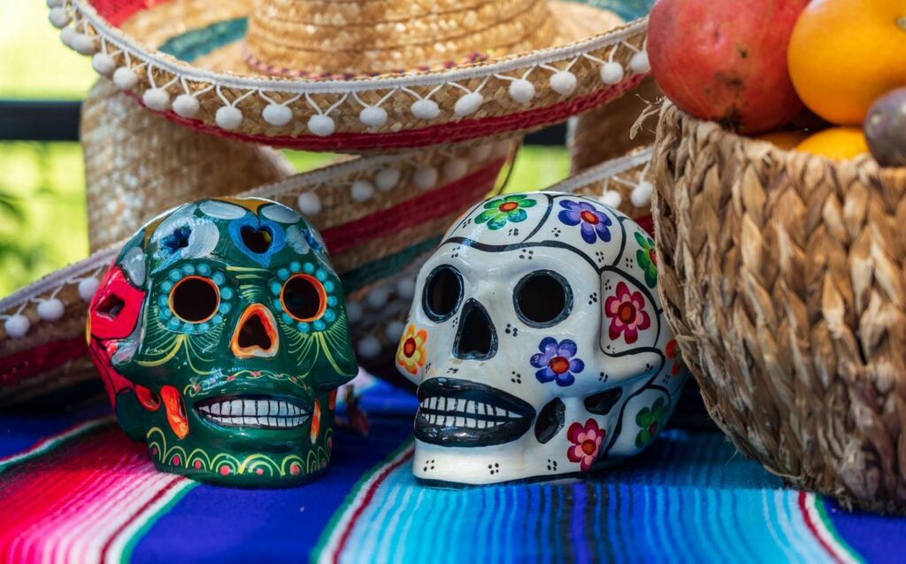 Two decorative skulls are found resting on a Mexican textile piece in celebration of Dia de Los Muertos, also known as Day of The Dead.